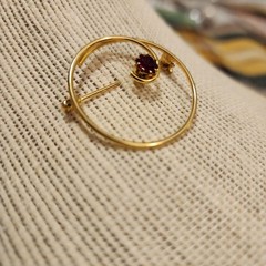 Gold Tone Swirl Circle Brooch With Red Rhinestone Accent.