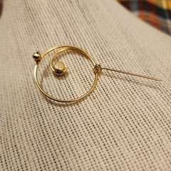 Gold Tone Swirl Circle Brooch With Red Rhinestone Accent.